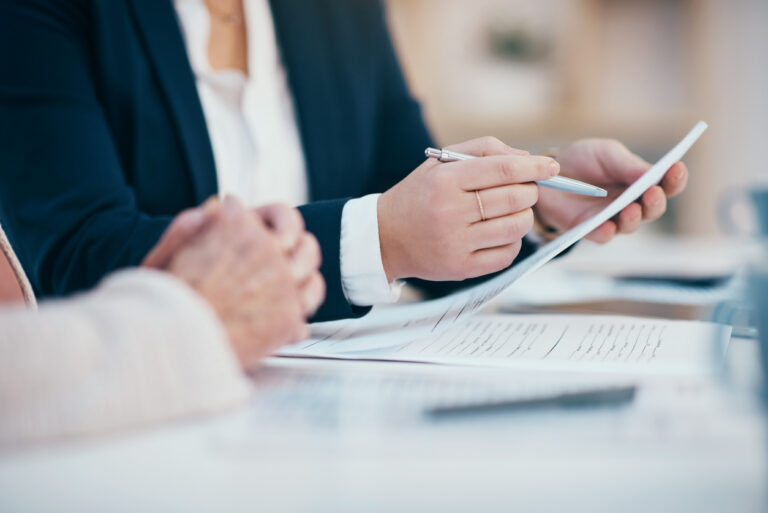 Hands closeup on contact, legal settlement or financial report while reading and making notes. Lawyer team doing work and analyzing documents. Lawyers looking through client finance data together
